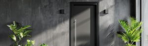 Modern black aluminum front door with vertical pull handle and minimalist dark facade with greenery